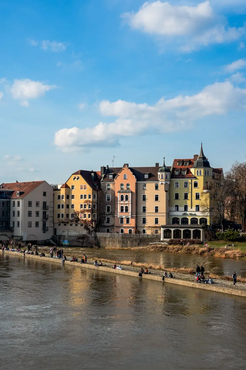 Menschen sitzen an einem sonnigen Tag an der Donaulände